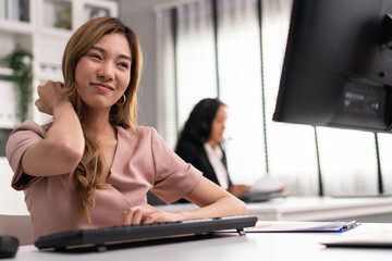 Asian employee woman massaging her neck and shoulder getting pain from office syndrome. Tensed...