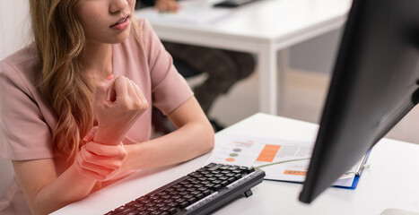 Woman employee holding wrist feeling pain from office syndrome. Hand hurt from using computer. health problem while working at workplace