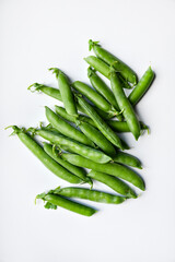 Pods of fresh green peas on a white background.