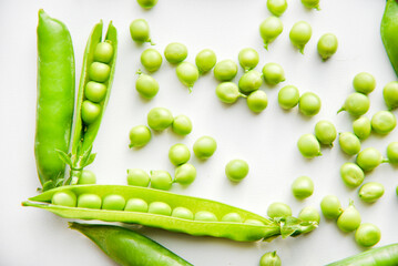 Pods of fresh green peas and green scattered peas.