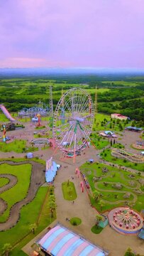 Top view of amusement park with Ferris wheel and roller coaster at sunset in Georgia at Tsitsinatela Park. Ferris wheel with air illumination. Recreation area of Georgian park on Black Sea coast.