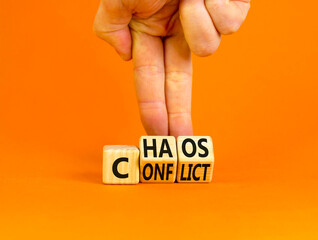From conflict to chaos symbol. Concept words Conflict and Chaos on wooden cubes. Businessman hand. Beautiful orange background. Businessman hand. Business Conflict and Chaos concept. Copy space.