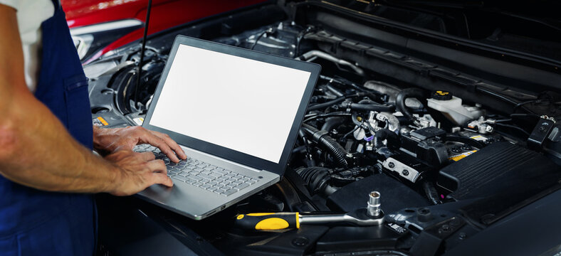engine diagnostics - car mechanic using laptop computer to diagnose vehicle motor in repair shop. blank screen copy space