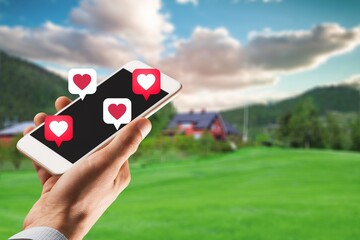 Human hand hold using smart phone with heart icon at outdoor park street background.