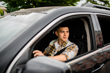 A young man driving a car looks out the window.