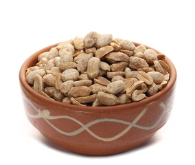 Pile salted and marinated peanuts in clay pot isolated on white  