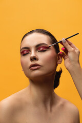 Obraz na płótnie Canvas Beautiful young woman makes shine on her face using makeup brush on the yellow background. Caucasian girl does makeup. makeup brushes
