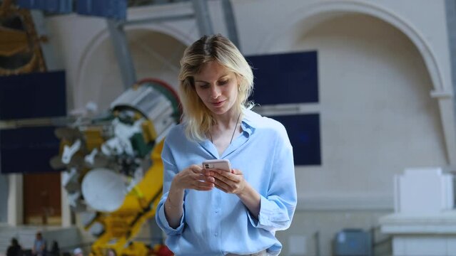 Caucasian woman uses a smartphone on the background of a space satellite