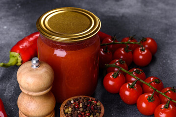 Spicy sweet tomato sauce with garlic, pepper and herbs in a glass jars