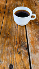 White cup of coffee, on a wooden table, contrasts that inspire.