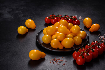 Pear-shaped small yellow tomatoes in a ceramic plate on a dark concrete table
