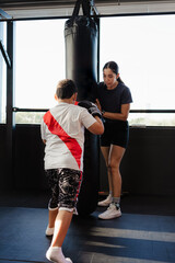 female kick boxing coach training a boy in gym
