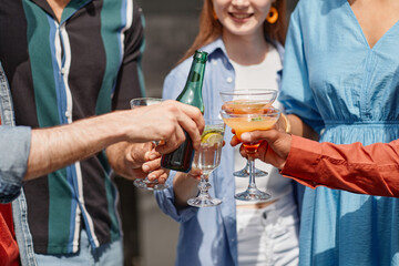 Close up of multiethnic friends enjoying drinks at outdoor party in sunlight