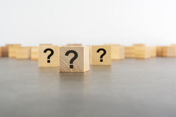 cube with question mark on wooden background. space for text