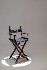 Directors chair stands in the beam of light. Space for text. The concept of selection and casting. Shadow and light.