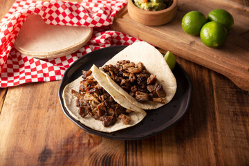 Tacos de Bistec. Homemade grilled meat in a corn tortilla. Street food from Mexico, traditionally accompanied with cilantro, onion and spicy sauce or guacamole