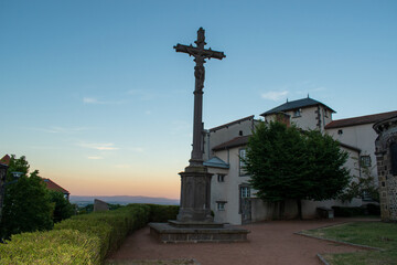 Fototapeta na wymiar Croix de mission en pierre de Volvic et coucher de soleil sur la plaine de Limagne, Volvic, Auvergne, France
