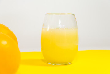 yellow grapefruits artistically placed on yellow table, glass of orange juice