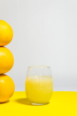 yellow grapefruits artistically placed on yellow table, glass of yellow grapefruit juice