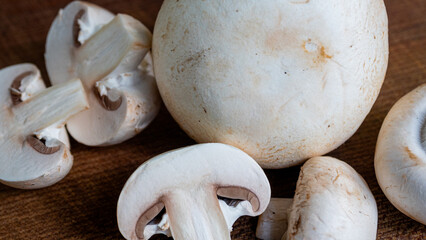 White mushrooms, chopped up in bite size pieces and bundled together on a dark brown chopping board.
Kitchen inspiration and food preparation concept.
