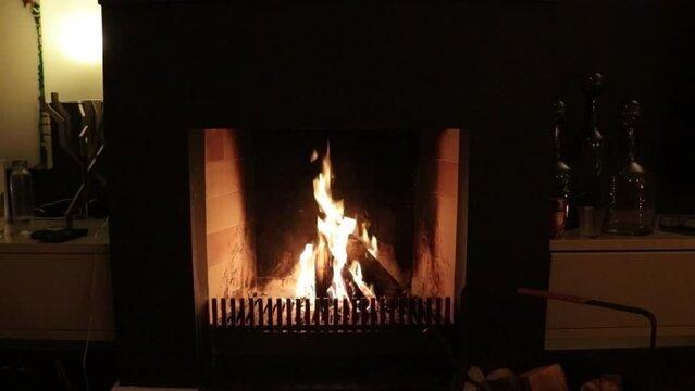 Close up of burning firewood in an inside fireplace during a dark evening.