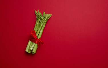 Bunch of fresh asparagus on red background, top view