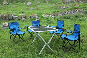 Camping kit folding metal table and four blue chairs.