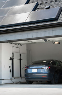 Solar Panels on a Roof Charging an Electric Vehicle and Home Battery Backup System in a Garage