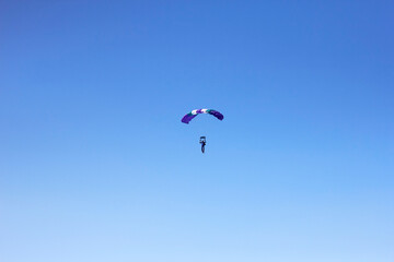 Flight of an experienced paratrooper with a professional parachute in the sky, orientation and landing on accuracy
