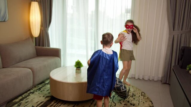Children playing superheroes jumping, children's pillow fight game, children in red and blue suits playing Supermen, Superheroes, bro and sister,playing at home, freaking out that they are superheroes