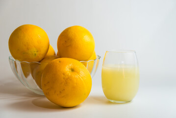yellow grapefruit in glass fruit bowl on yellow table, glass of milk