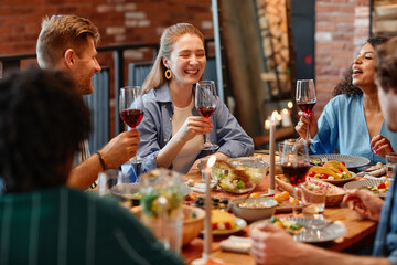 Portrait of young woman laughing happily during dinner party with friends in cozy setting