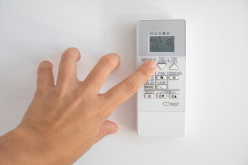 Hand turning on an air conditioning control, where 19 degrees are seen on the screen, as recommended by the new regulations of the Spanish government for winter