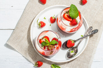 Italian dessert panna cotta in glass with strawberries. Healthy sweet food, hard light, dark shadow
