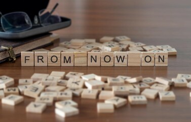 from now on word or concept represented by wooden letter tiles on a wooden table with glasses and a book