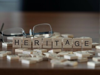 heritage word or concept represented by wooden letter tiles on a wooden table with glasses and a...