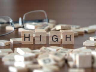 high word or concept represented by wooden letter tiles on a wooden table with glasses and a book