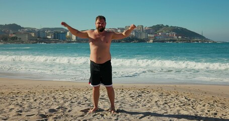A man rotates his hands on the beach, morning exercises.