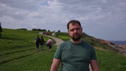 A man walks through a park along the ocean.