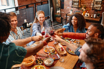 High angle view of young people clinking glasses while celebrating together at dinner party in cozy setting, copy space