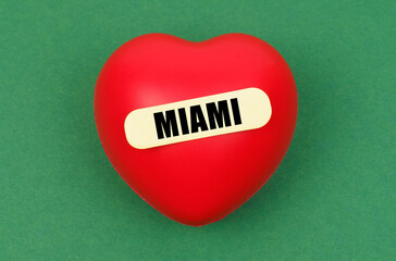 On a green surface lies a red heart with the inscription - Miami