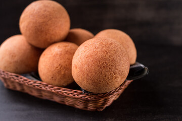 Round colombian traditional food named buñuelo in a basket on black wooden table 