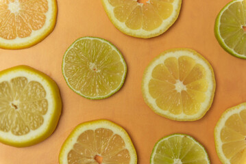 Fototapeta na wymiar Fresh cut lemon and lime slices on orange background