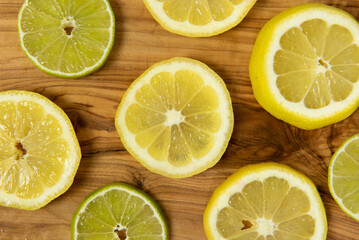 Fresh cut lemon and lime slices on grainy wooden rustic background