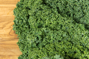 Bunch of organic fresh kale on grainy wooden background.
