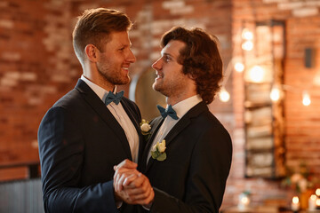 Portrait of male gay couple dancing together during wedding ceremony and holding hands, copy space