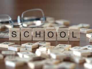 school word or concept represented by wooden letter tiles on a wooden table with glasses and a book