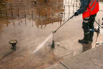 A man uses an electric pressure washer for a pressure washer. Cleaning city fountains in autumn. Workers remove the dirt that has settled during the season.