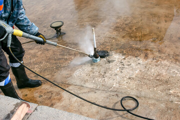 A man uses an electric pressure washer for a pressure washer. Cleaning city fountains in autumn....