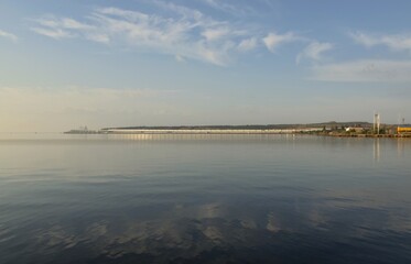Walk at dawn along the embankment of the city of Kerch, Russia, summer morning seascape, view of the Crimean bridge, the concept of travel and recreation.